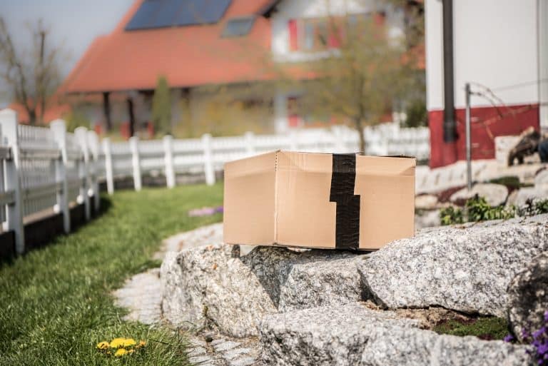 Postbote legt Paket Schachtel im Garten des Nachbarn ab